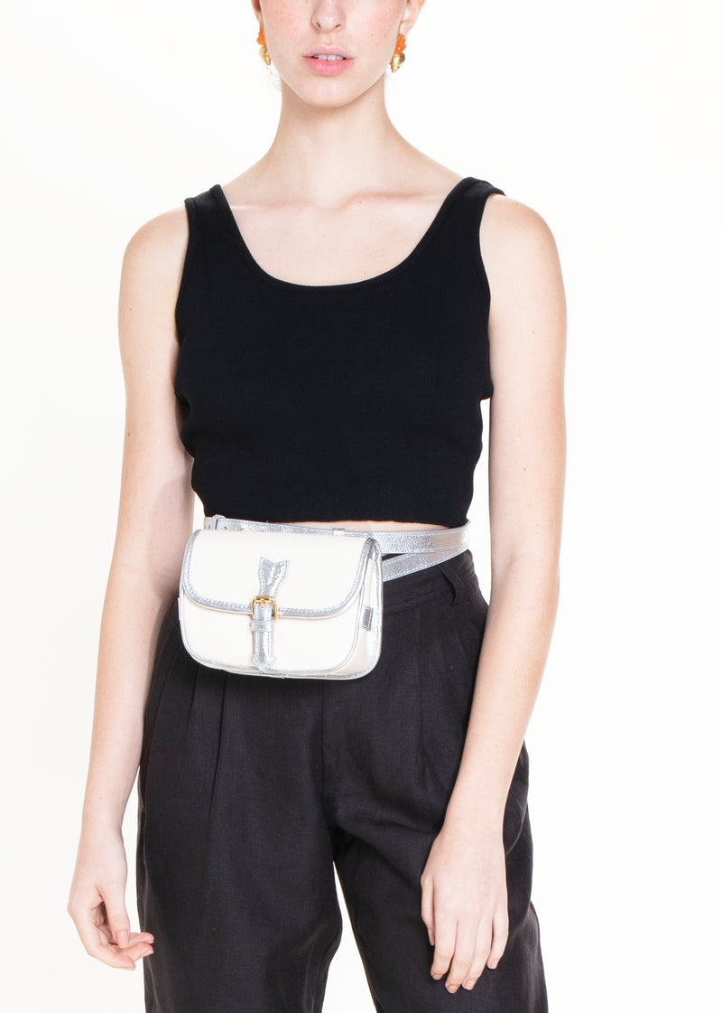 Bolsa estruturada em canvas cru, com couro metálico prata nos acabamentos, fivela dourada e versatilidade de uso como crossbody ou pochete.
