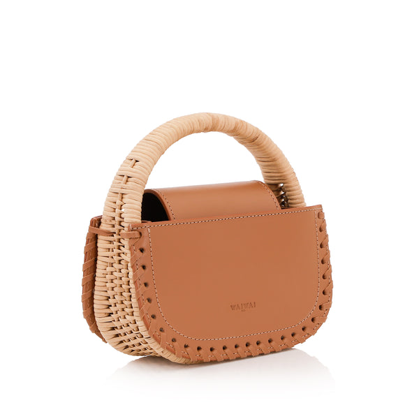 Bolsa de couro marrom claro com detalhe de costura trançada nas laterais e alça estruturada revestida em vime natural.