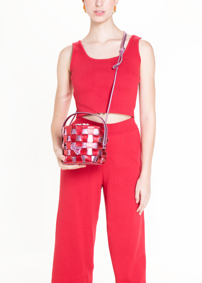 Bolsa bucket estruturada com trama em couro vermelho e rosa, alça curta e fecho regulável em cordão.