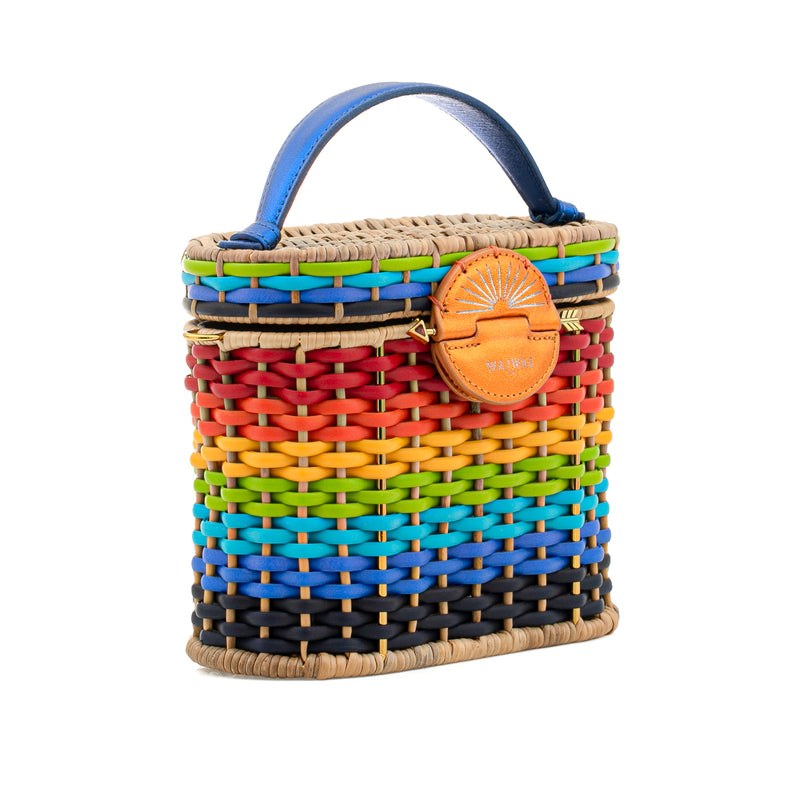 Bolsa em palha estruturada, com trama multicolorida em degradê arco-íris, fecho redondo em couro laranja com símbolo de sol, alça curta em couro azul e detalhes em fibras naturais.