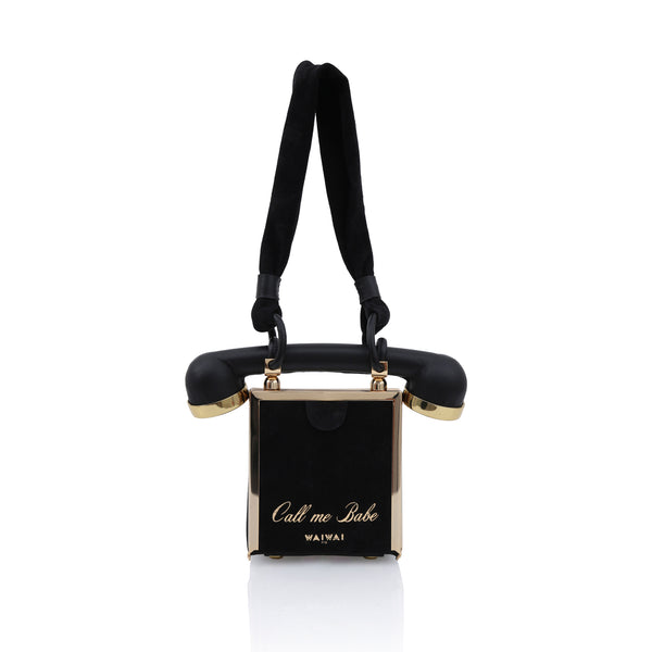 Bolsa em formato de telefone retrô preta, com disco frontal dourado e alça rígida em formato de fone.