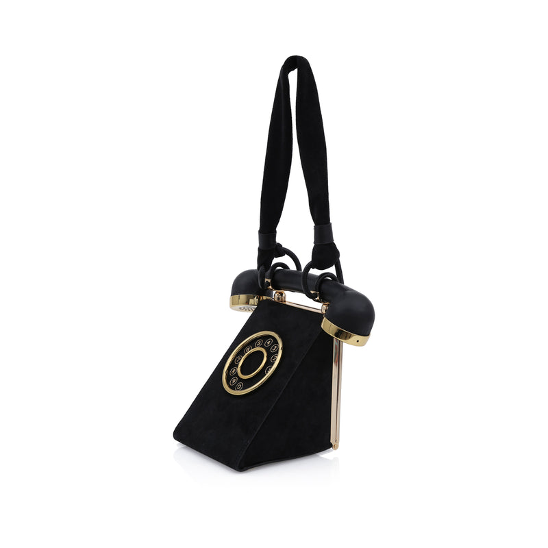Bolsa preta em estilo retrô, formato de telefone com disco dourado frontal e alça estruturada semelhante ao fone.