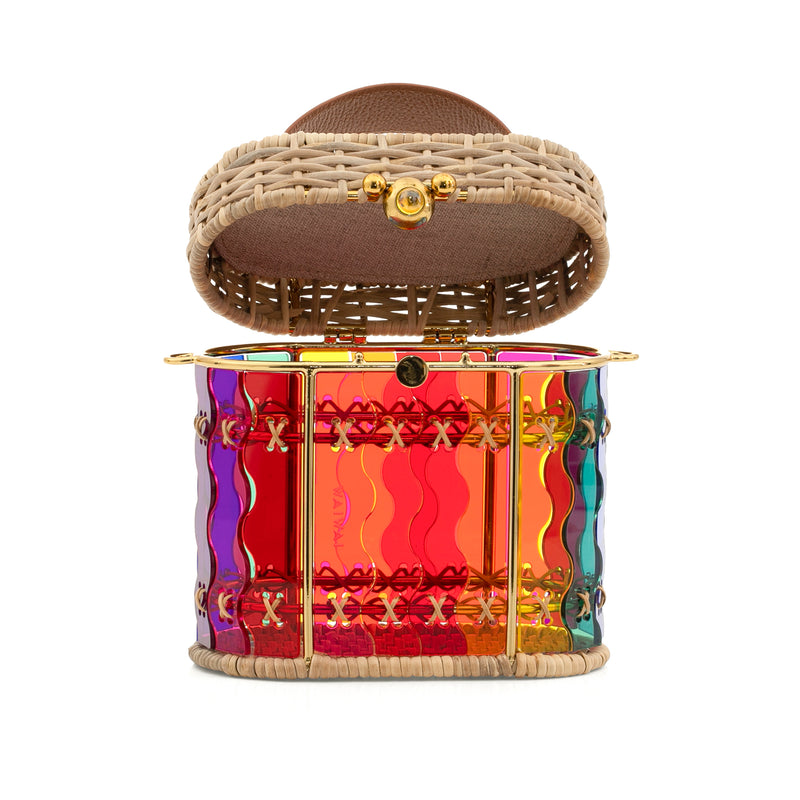 Bolsa em acrílico arco-íris com design ondulado, estruturada com laterais em rattan, ferragens douradas e alça de mão em couro marrom.