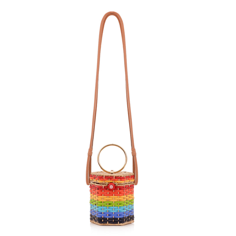 Bolsa estruturada em rattan com trama em degradê de cores do arco-íris, fecho esférico vermelho e alça metálica circular dourada.