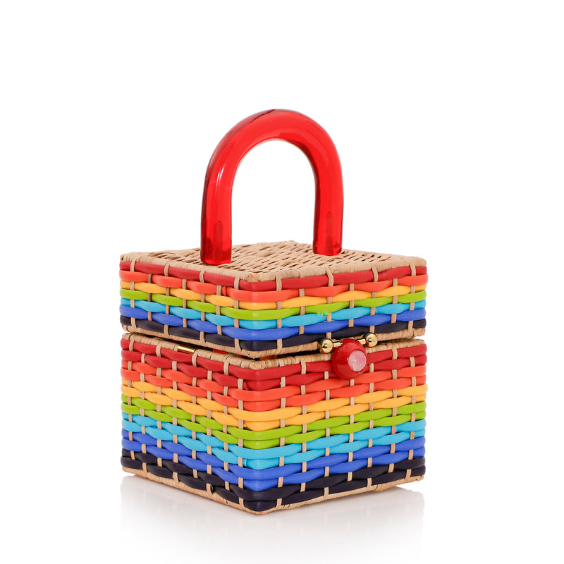 Bolsa estruturada em rattan com trama em cores do arco-íris, alça rígida em acrílico vermelho e fecho esférico vermelho central.