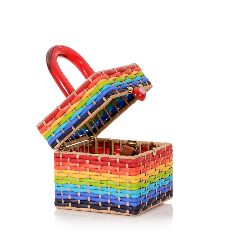 Bolsa estruturada em rattan com trama em cores do arco-íris, alça rígida em acrílico vermelho e fecho esférico vermelho central.