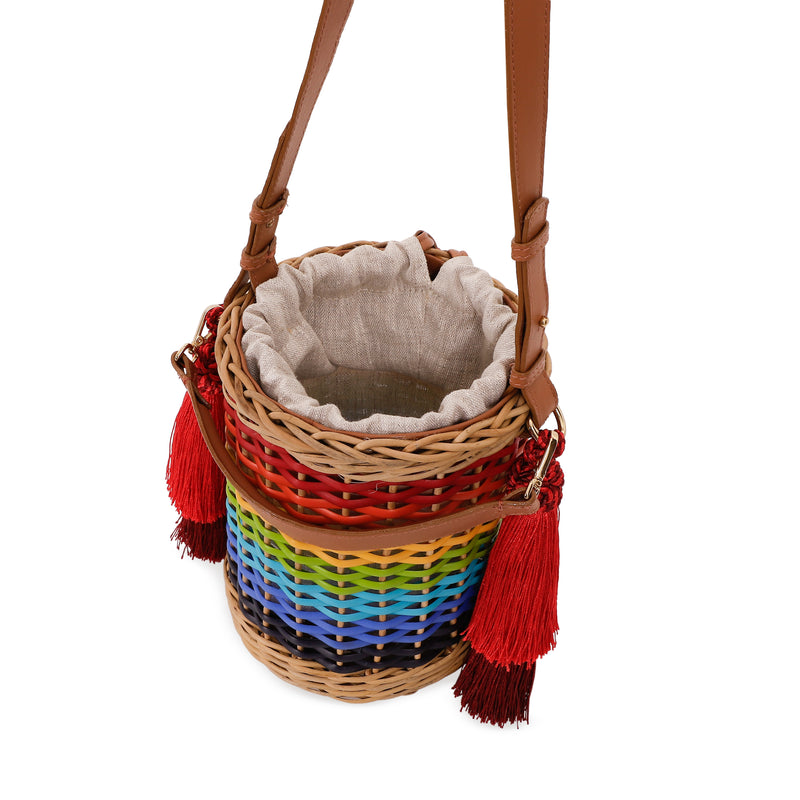 Bolsa estruturada em rattan com trama em degradê de cores do arco-íris, alça longa em couro marrom e tassels vermelhos laterais.