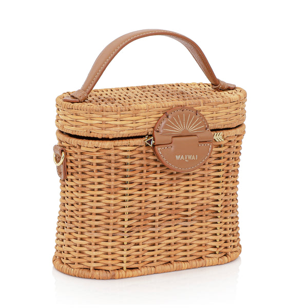 Bolsa de rattan natural com alça curta em couro bege e fecho circular em couro com detalhe em formato de raio de sol dourado.
