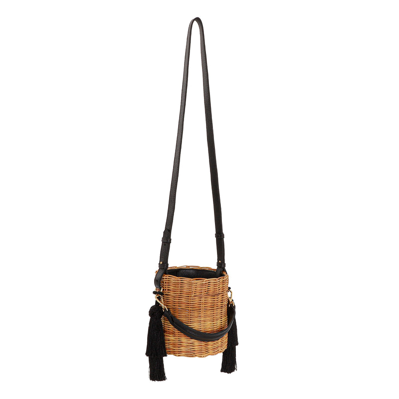 Bolsa tiracolo estruturada em rattan natural com alça longa em couro preto e detalhes em tassels pretos laterais.