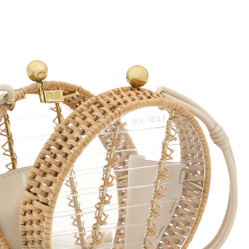 Bolsa circular em acrílico transparente estruturado, com bordas em rattan natural, alça longa bege removível, fecho dourado de esferas e divisórias internas em couro bege.