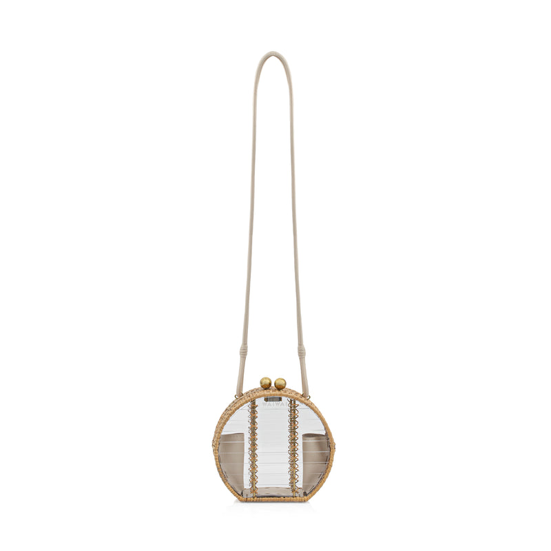 Bolsa estruturada em formato redondo, feita em acrílico transparente com bordas em rattan natural, alça longa removível em couro bege e fecho metálico esférico dourado.