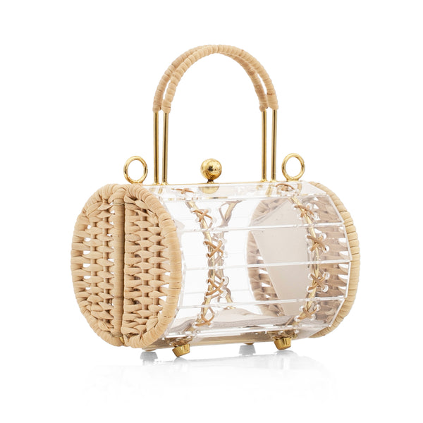Bolsa estruturada em acrílico transparente, laterais em couro bege, acabamentos em metal dourado e alça curta de palha natural.
