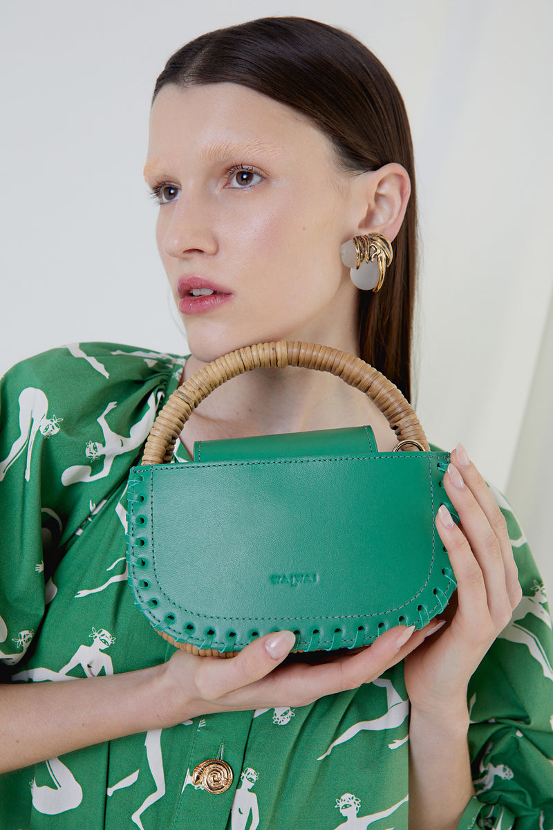 Bolsa estruturada em couro verde com bordas costuradas e alça curta em rattan. Estilo sofisticado.