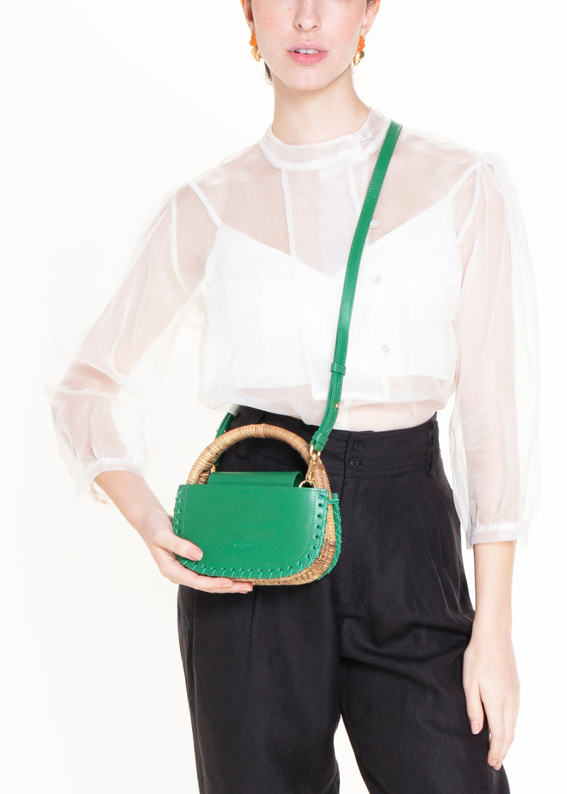 Bolsa de couro verde com detalhe de costura nas laterais e alça em rattan estruturado.