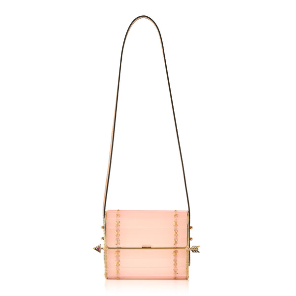 Clutch em acrílico rosa translúcido com laterais em rattan, detalhe de costura em X dourado e fecho em formato de flecha metálica dourada com ponta vermelha.