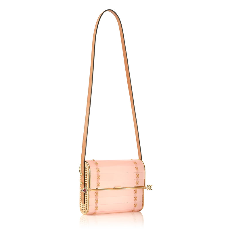 Clutch em acrílico rosa translúcido com laterais em rattan, detalhe de costura em X dourado e fecho em formato de flecha metálica dourada com ponta vermelha.
