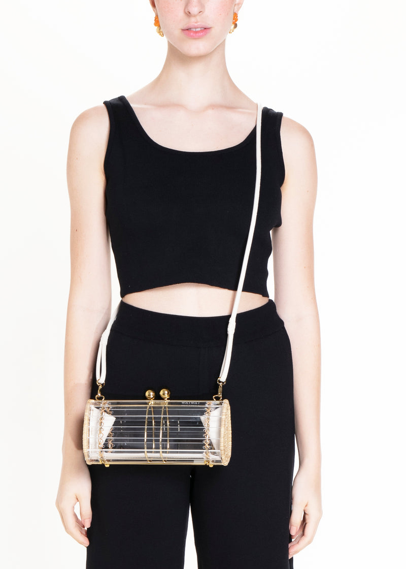 Clutch retangular em acrílico transparente com laterais em rattan, detalhe de costura em X e fecho esférico dourado.