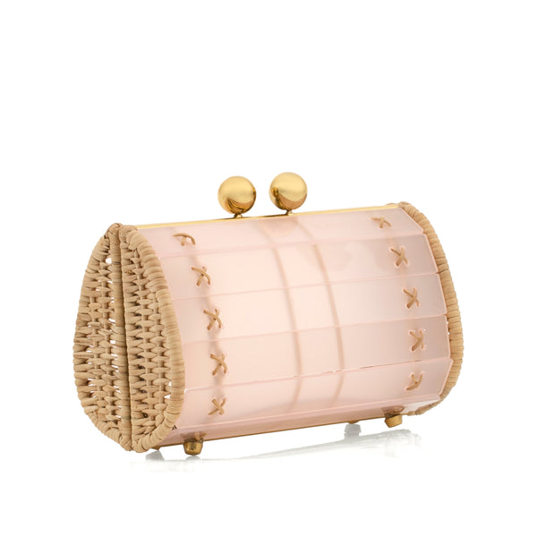 Clutch pequena em acrílico rosa fosco estruturado, laterais em rattan natural, ferragens douradas e fecho superior com duas esferas metálicas.