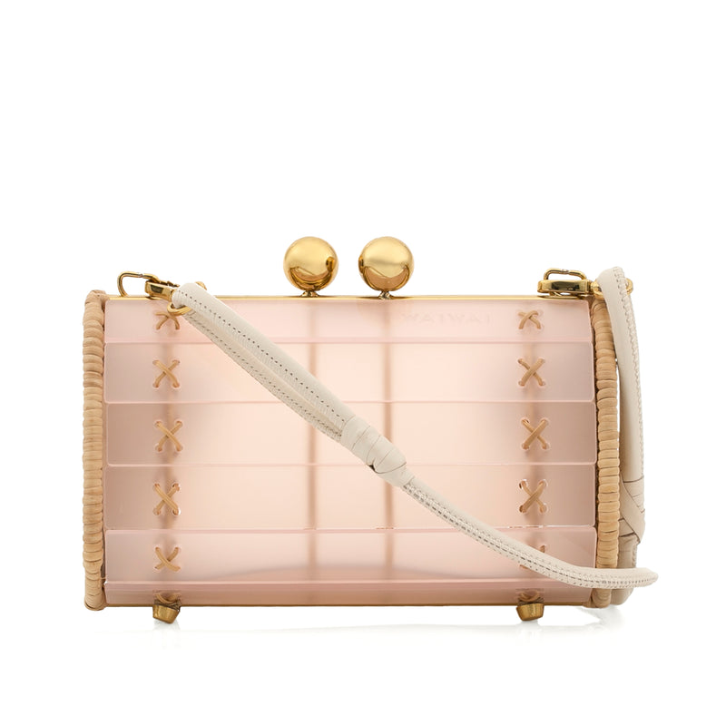 Bolsa clutch em acrílico rosa fosco, laterais em rattan natural, ferragens douradas e fecho de duas esferas metálicas douradas.