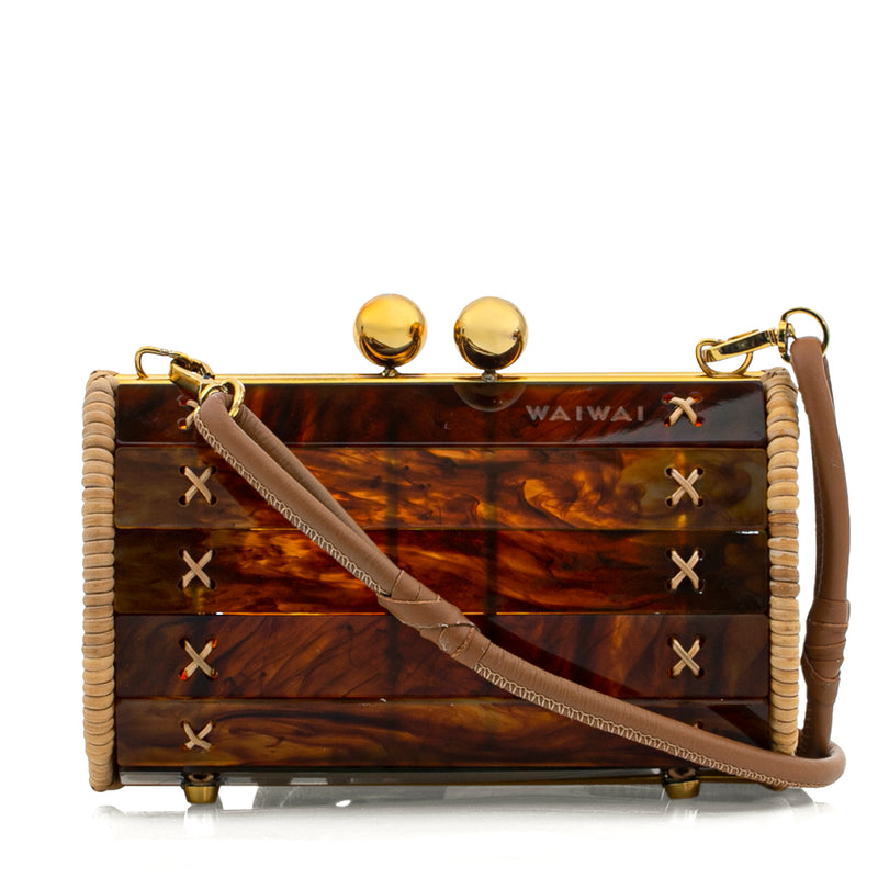 Bolsa clutch em acrílico marrom efeito tartaruga, estruturada com laterais em rattan natural e detalhes dourados no fecho e ferragens.