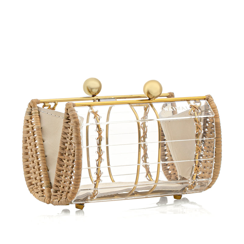 Clutch estruturada pequena em acrílico transparente, com laterais de rattan natural, amarrações em couro bege e fecho dourado esférico no topo.